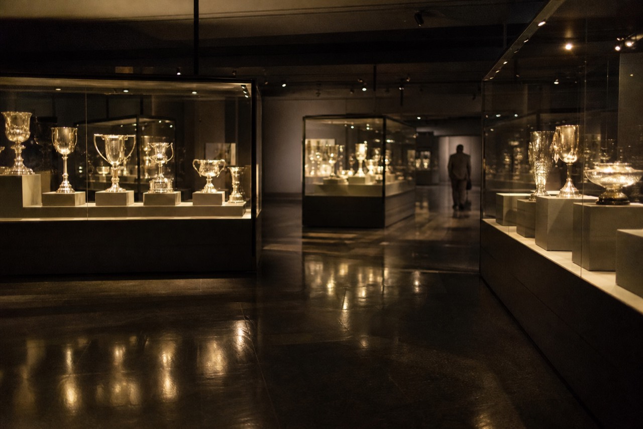 Interactive touchscreen displays glowing along a dark football club museum gallery