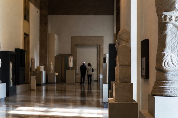 Dimly lit museum gallery with tall glass cases holding pre-Columbian ceramics and gold objects