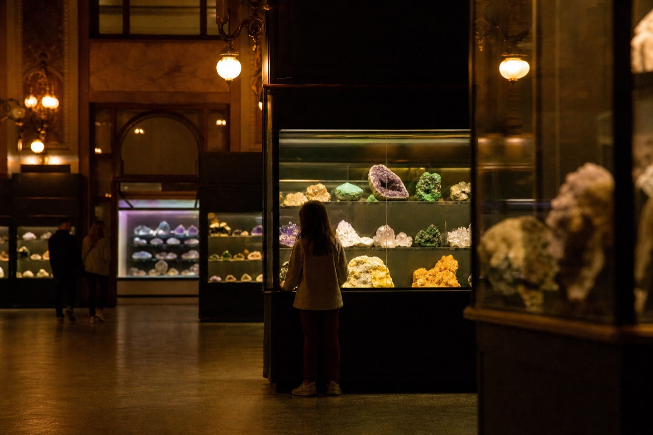 Glass cases of polished minerals and crystals lit against dark walls in a geology gallery