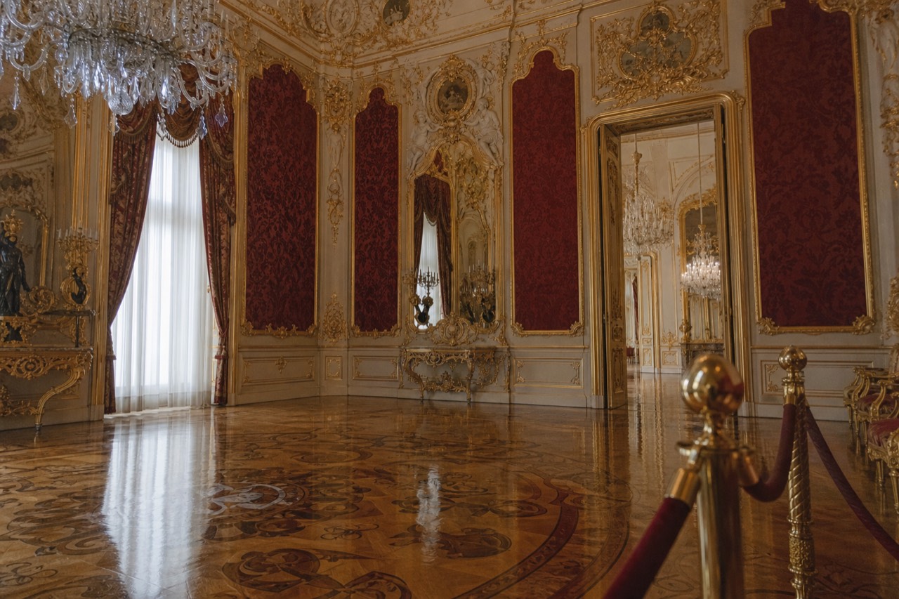 Wide stone staircase with a painted ceiling and gilded balustrade inside a royal palace